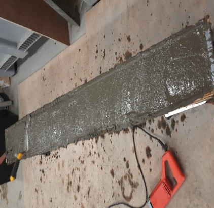 A person using a tool to cut a cement slab Description automatically generated